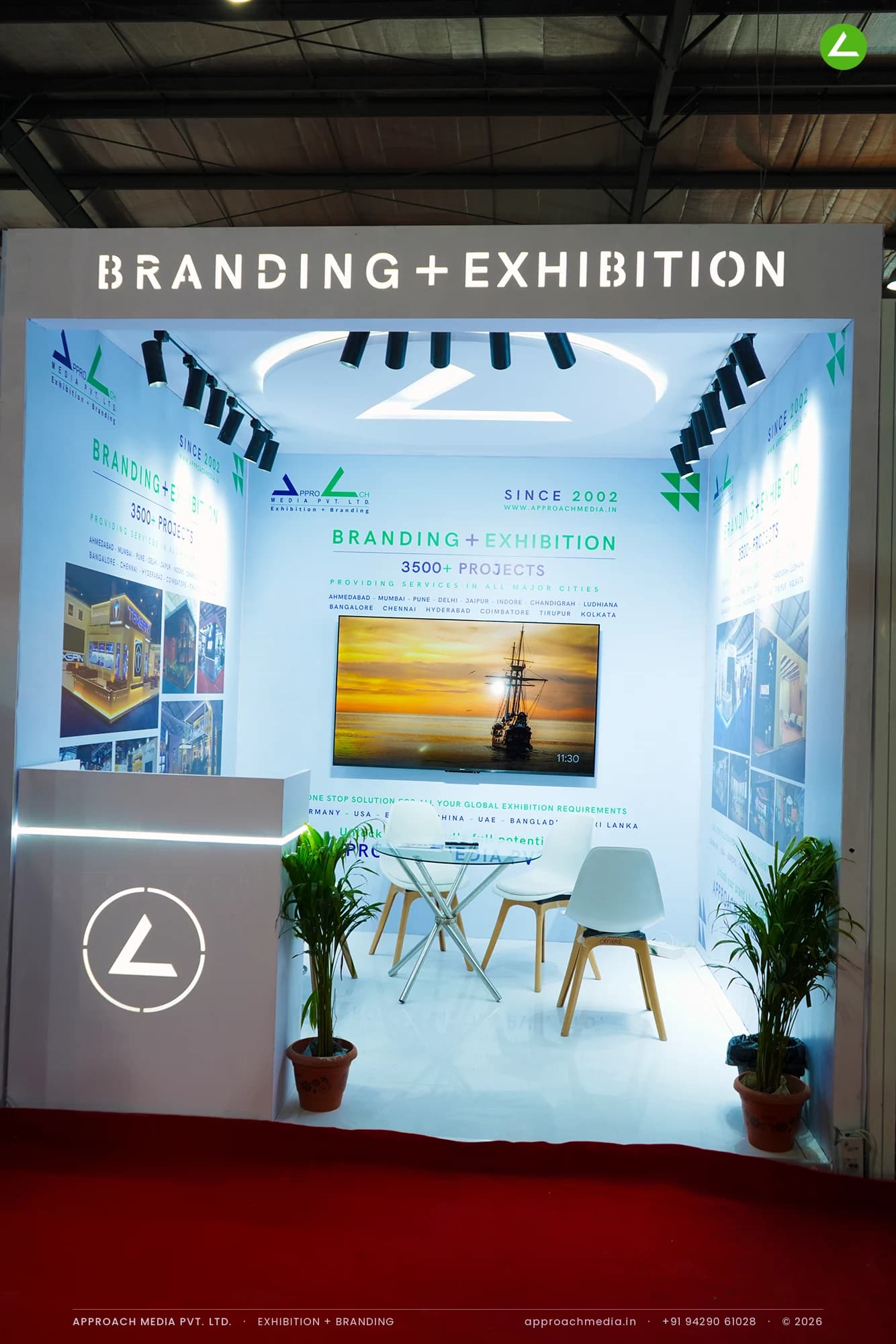 Approach Media exhibition stall design at GPBS Gandhinagar, a white 9 sqm stand with project photo walls and track lighting