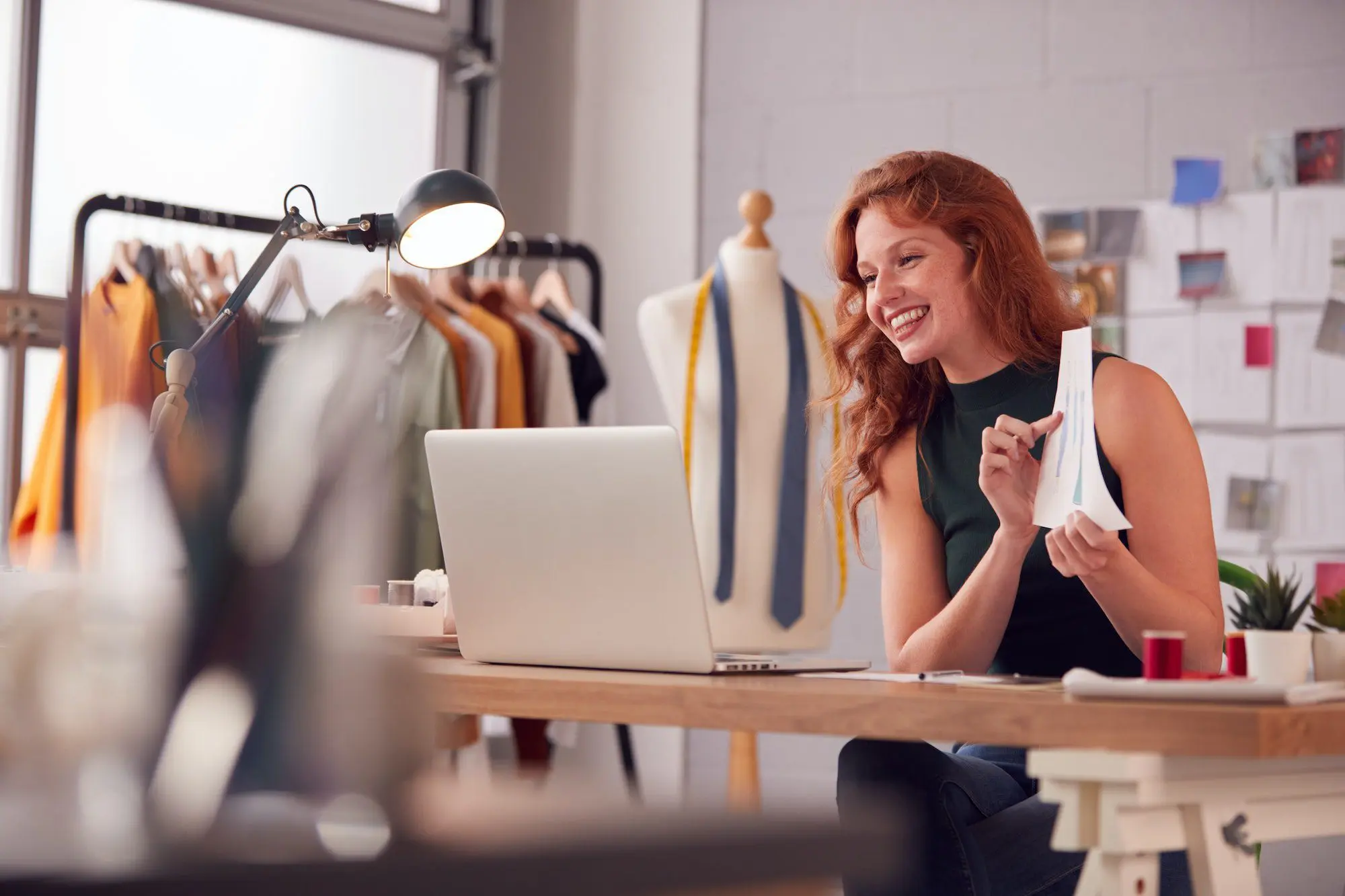 Female Business Owner Working In Fashion Showing Designs On Video Call Using Laptop