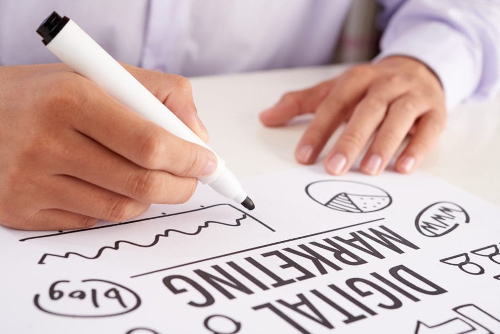 Crop hands making notes on digital marketing scheme