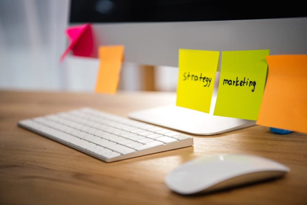 close up view of colorful sticky notes with marketing and strategy lettering on computer screen at